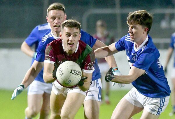 Portarlington's Darragh Slevin releasing this ball with Tadhg Roche (Old Leighlin) looking to disrupt Photo: Denis Byrne