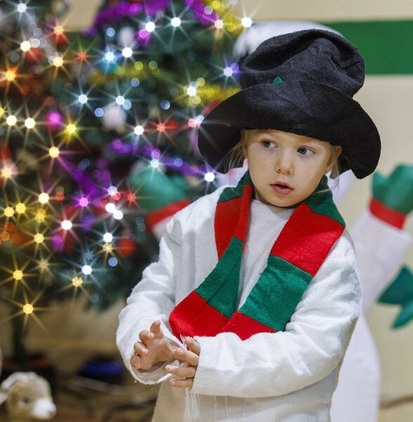 A young child dressed as a snowman sizes up the audience before their performance