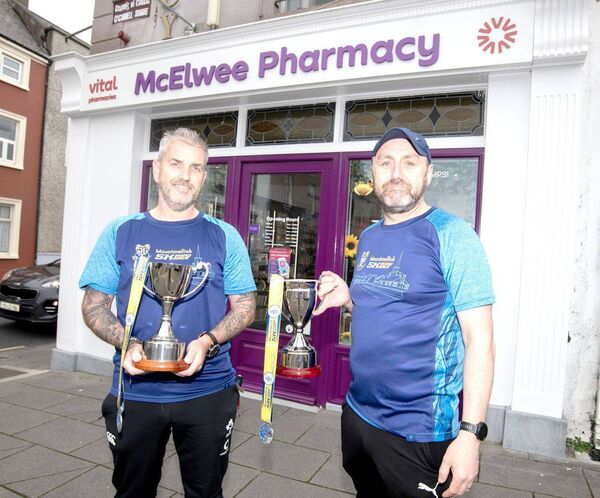 Pictured at McElwee Pharmacy (Sponsor) are Darren Brooks and Gary Devane Road Runner Athletic Club Mountmellick with The Noel Coss &amp; Michelle Oxley Perpetual Cups