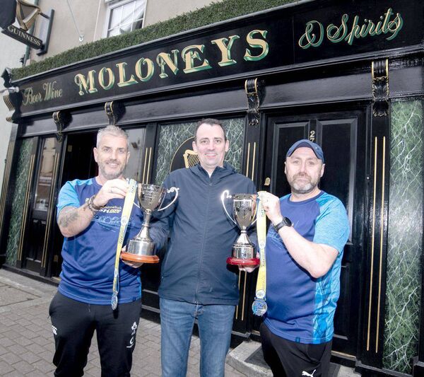 Pictured are John Moloney Jnr Proprietor "Moloneys Bar" (Sponsor) with Darren Brooks and Gary Devane Road Runner Athletic Club Mountmellick with The Noel Coss &amp; Michelle Oxley Perpetual Cups 